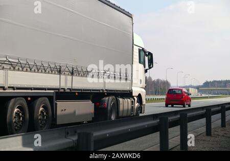 Autobahn. Zwei verschiedene Verkehrsteilnehmer: Ein großer Lastwagen und ein kleiner Pkw. Stockfoto