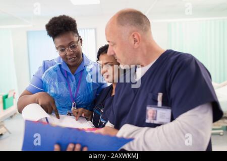 Ärzte und Pfleger mit medizinischen Chart, die Runden führt, Beratung im Krankenhauszimmer Stockfoto