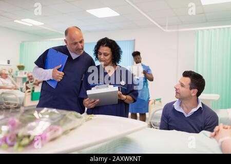 Ärzte mit medizinischen Diagrammen machen Runden in der Krankenstation Stockfoto