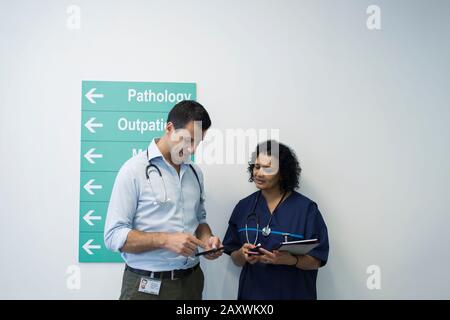 Ärzte mit Smartphones sprechen im Krankenhausflur Stockfoto