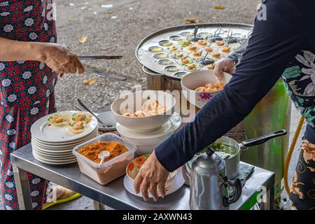 Vietnamesische Händler, die knusprige Garnelenpfannkuchen beim Straßenhändler machen Stockfoto