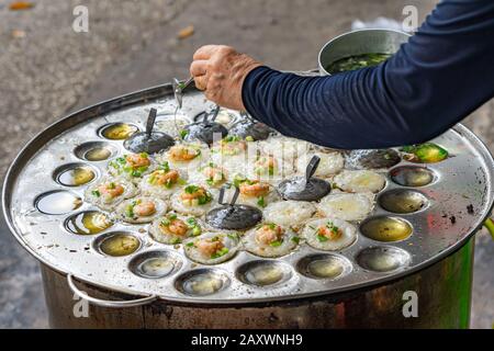 Hawker macht vietnamesische winzige Garnelenpfannkuchen - Banh Khot Stockfoto