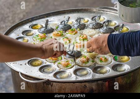 Händler, der vietnamesische Garnelenpfannkuchen anstellt - bann Khot Stockfoto