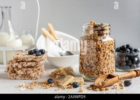 Hausgemachtes, bereites Frühstücksgranola, Müsli mit frischen, reifen Blaubeeren, weißer Schokolade und Milch. Nahaufnahme, nützliches Produkt, Hintergrund Stockfoto