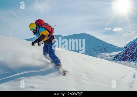 Ein junger Mann reitet auf einem Snowboard. Unberührter Schnee in den Bergen. Berge kirgisistans Stockfoto