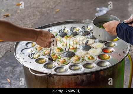 Händler, die Banh Khot - Vietnam mit knusprigem Garnelenpfannkuchen würzen Stockfoto