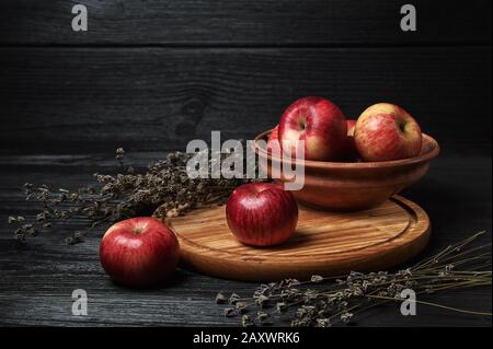 Stillleben, Äpfel auf schwarzem Grund umgeben von getrockneten Blumen Stockfoto
