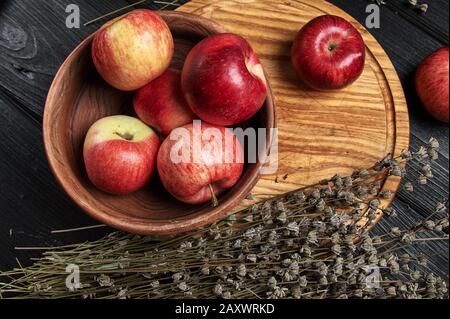Stillleben, Äpfel auf schwarzem Grund umgeben von getrockneten Blumen Stockfoto