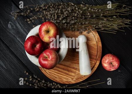 Stillleben, Äpfel auf schwarzem Grund umgeben von getrockneten Blumen Stockfoto