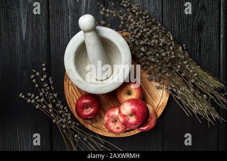 Stillleben, Äpfel auf schwarzem Grund umgeben von getrockneten Blumen Stockfoto