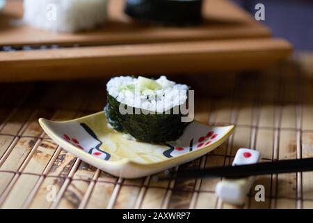 Nahaufnahme von Sushi auf Bambusmatte mit Essstäbchen in der Nähe. Stockfoto