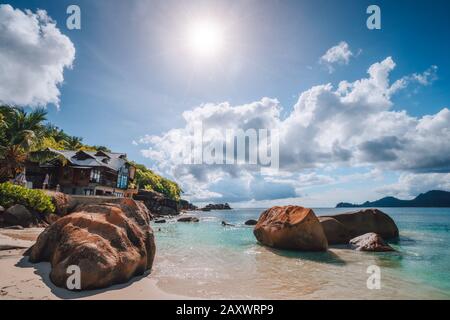 Strand von Anse Takamaka, Seychellen. Hotel am Strand, Sonne der Nonne platzt Licht über den Horizont des Ozeans Stockfoto