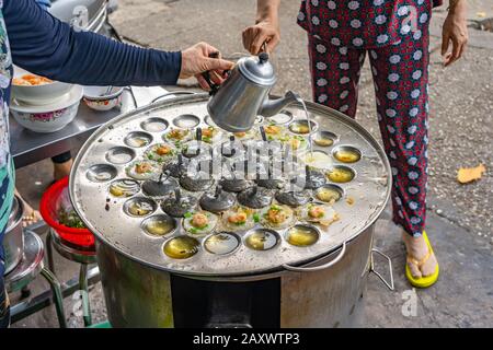 Straßennahrungsmittel, die vietnamesische Mini-Garnelen-Pfannkuchen machen - Banh Khot Stockfoto