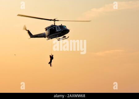 Triest, Italien - 27. September 2009: Italienischer Polizeihubschrauber mit am Seil verankerten Tauchern für den Transport von Männern über Bord. Stockfoto