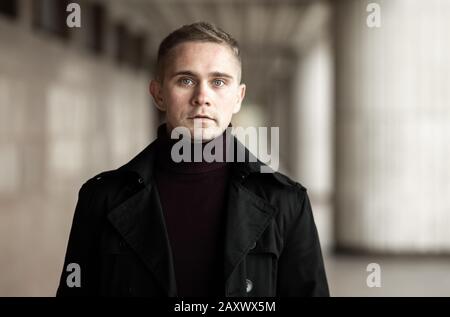 Stilvoller Mann mit schwarzem Trenchcoat und violettem Polokragen Stockfoto