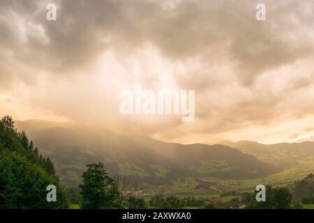 Das Gewitter über einem Berg wird bei Sonnenuntergang von hinten von der Sonne angestrahlt Stockfoto