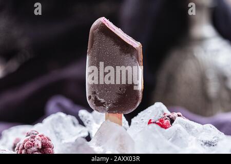 Schöne Aufnahme von hausgemachten veganen Eis bedeckt von Schokolade umgeben Mit Eiswürfeln Stockfoto