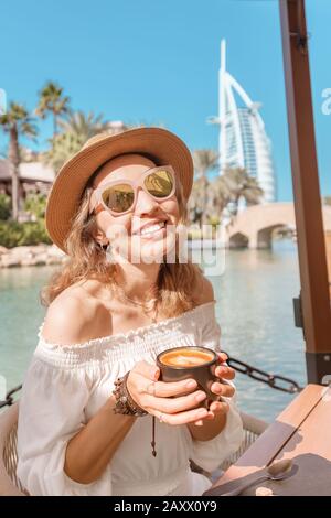 Glückliche asiatin trinkt Morgenkaffee im Hintergrund der Resortstadt Stockfoto