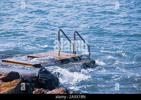 Nahaufnahme eines Anlegesteg mit Metalltreppen zum Meer zum Schwimmen Stockfoto