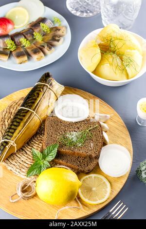 In Scheiben geschnittener gesalzter Fisch mit Zitrone und Gewürzen, gekochte Kartoffeln auf einem Tisch. Draufsicht Stockfoto