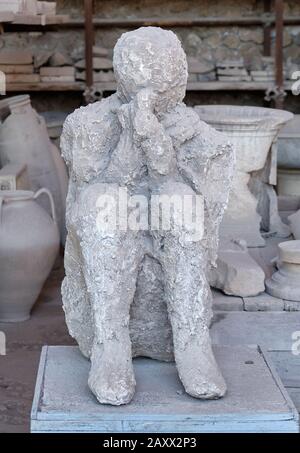 Dieser in Asche verschüttete und von giftigen Gasen erstickte, während er Mund und Nase bedeckt, ist in Pompeji, Italien ausgestellt Stockfoto