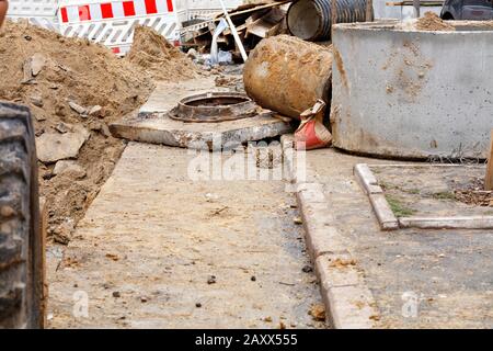 Das alte Kanalisationsmanloch und der Betonbrunnen müssen bei der Reparatur des städtischen Sammlers auf der Fahrbahn durch neue ersetzt werden. Kopierbereich. Stockfoto