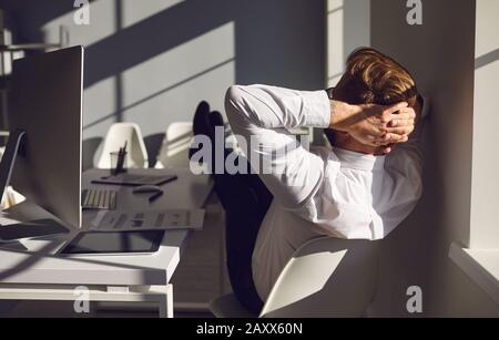 Der Geschäftsmann, der sich ausruht, entspannt mit einem Computer im Büro die Träume am Arbeitsplatz am Tisch Stockfoto