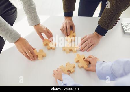 Gesichtslose Geschäftsleute, die Puzzleidee zusammenlegen Stockfoto