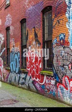 Graffiti, die auf die Ziegelwände einer Hintergasse im Gastown Distrikt von Vancouver Canada gemalt wurden Stockfoto