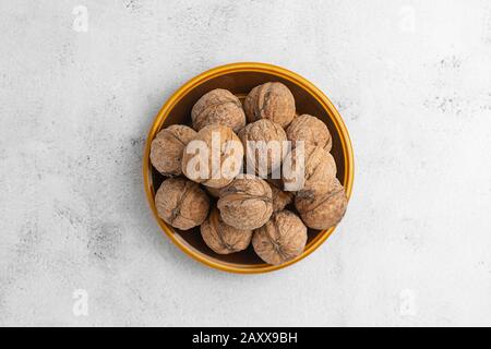 Walnüsse in runder Platte auf hell strukturierter Oberfläche. Gesunde Nüsse, gesunde Lebensmittel. Stockfoto
