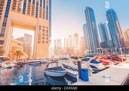 Parken von Booten und Yachten in der Dubai Marina vor dem Hintergrund hoher Wolkenkratzer und Hotels Stockfoto