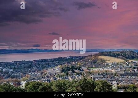 Blick vom Denkmal in Dundee Law hinab auf das Vierte der Tay Estuary in die weite, dunstige Entfernung, während die Sonne über die Stadt untergeht. Stockfoto