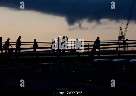 London, Großbritannien. Februar 2020. Sonnenuntergang, eine Pendlerüberfahrt Millennium Bridge hält an, um während der Flut im Frühjahr ein Bild nach Westen entlang der Themse zu machen. Kredit: Thamesfleet/Alamy Live News Stockfoto