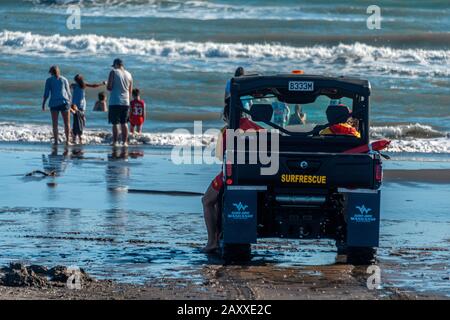 Neuseeländisches Surfrettungsfahrzeug mit Familie im Hintergrund, am schwarzen Eisen-Vulkansand des Castlecliff Beach in Whanganui. Stockfoto