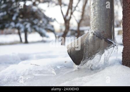 Drainpipe an der Hausecke mit Eis bedeckt. Stockfoto