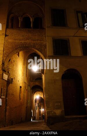 Siena in der Nacht. Beleuchtete Straße in der Nacht im Zentrum von Siena. Stockfoto