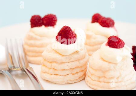 Dekorative, gewellte Konusmeringues mit frischer Schlagsahne gefüllt und mit reifen roten Erdbeeren bekrönt Stockfoto