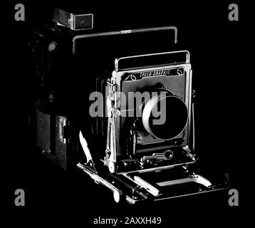 Vintage Speed Graphic, hergestellt von Graflex in Rochester, NY, Mittelformatfilmkamera, schwarzer Hintergrund, Beleuchtung mit niedriger Tonart. Schwarzweißfoto. Stockfoto
