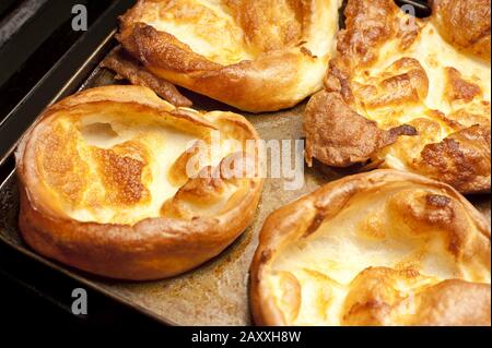 Große, frisch gebackene goldene Yorkshire Puddings auf einem Holzbrett in der Küche, die zum Abendessen serviert werden kann, Nahaufnahme mit Blick in den hohen Winkel Stockfoto