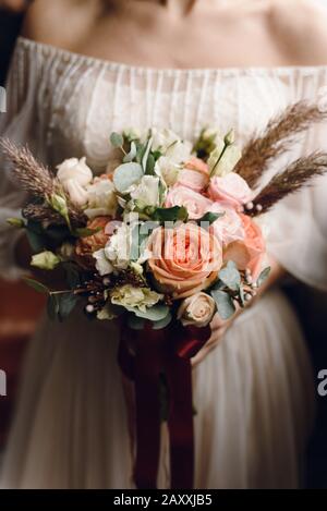 Zarte, stylische Rosenstrauß, Ponys in den Händen der Frau in einem Hochzeitskleid. Vertikales, wunderschönes Hochzeitskonzept. Stockfoto