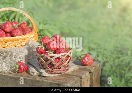 Erdbeeren mit Blättern im Korbkorb. Frische Erdbeere im Korb auf Holztisch auf verschwommenem Hintergrund. Kopieren Sie Speicherplatz für Ihren Text Stockfoto