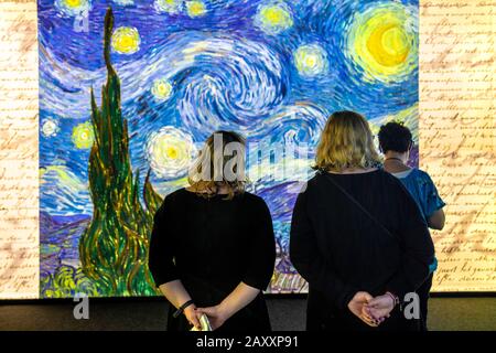 Besucher, die Van Goghs 'Starry Night' auf einer digitalen Wand im Meet Vincent van Gogh Experience 2020, London, Großbritannien, sehen Stockfoto