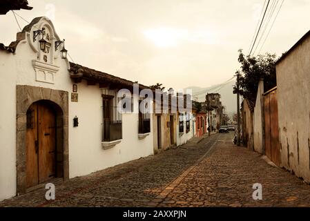 Malerischer Straßenblick mit Kopfsteinpflaster und spanischen Kolonialgebäuden bei Sonnenuntergang. Antigua, Guatemala. Januar 2019 Stockfoto