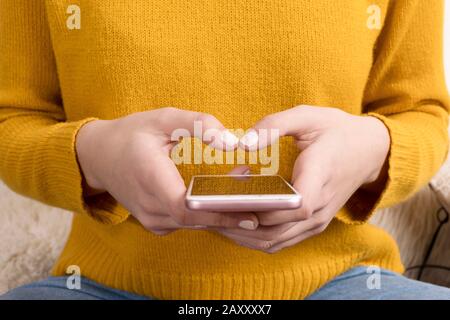 Frau im gelben Trikot - mit Smartphone Stockfoto