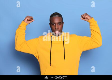 Junger afrikanischer schwarzer Mann, der die Faust hebt, sich glücklich und erfolgreich fühlt. Stockfoto