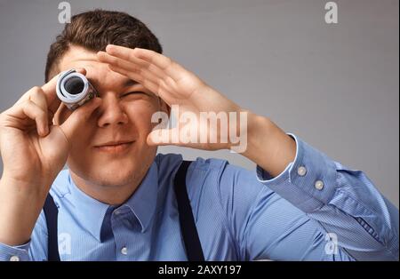 Der Geschäftsmann blickt durch eine Tube Geld auf die Welt Stockfoto