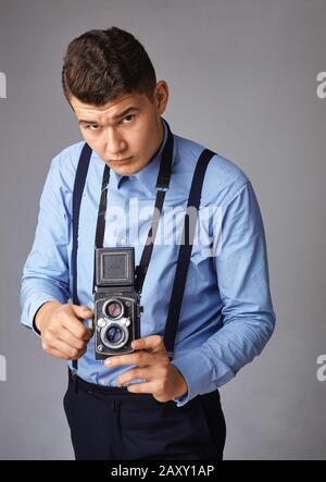 Guy mit der alten Kamera im Studio. Guy schießt auf eine alte Vintage-Filmkamera mit zwei Objektiven. Stockfoto