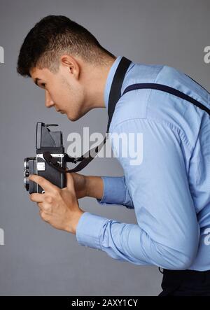 Guy mit der alten Kamera im Studio. Guy schießt auf eine alte Vintage-Filmkamera mit zwei Objektiven. Stockfoto