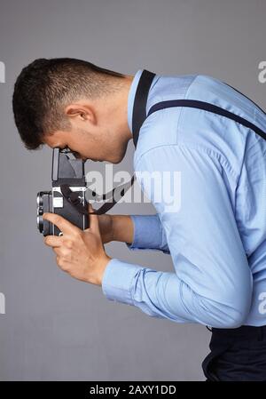 Guy mit der alten Kamera im Studio. Guy schießt auf eine alte Vintage-Filmkamera mit zwei Objektiven. Stockfoto