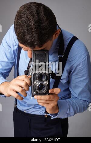 Guy mit der alten Kamera im Studio. Guy schießt auf eine alte Vintage-Filmkamera mit zwei Objektiven. Stockfoto